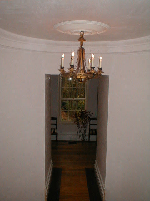 The oval upper hall by candlelight, chandelier glowing, curved cornice and domed ceiling